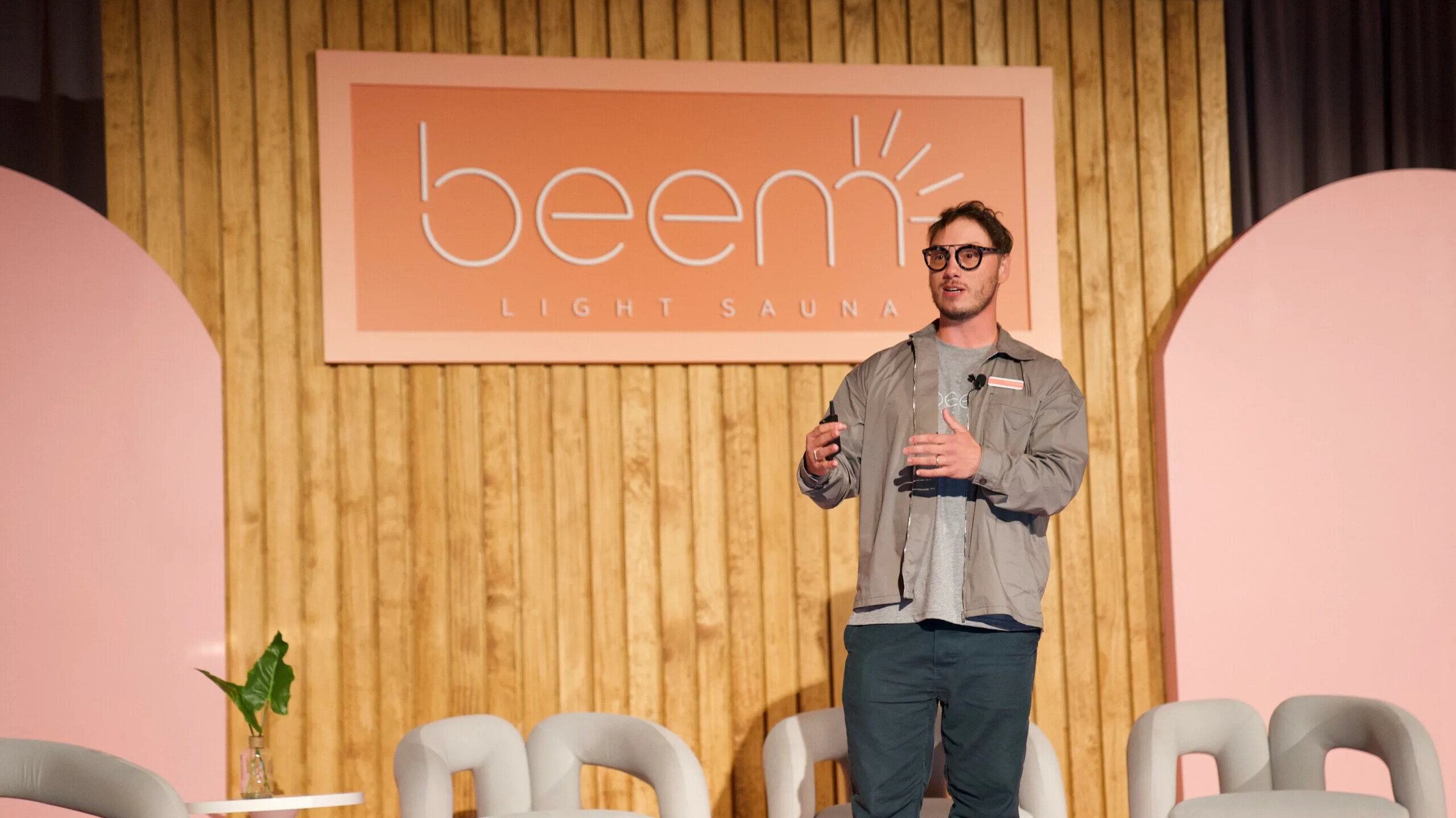 Beem leader presents on stage in front of Beem Light Sauna sign and panel set up