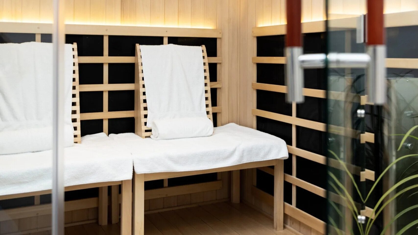 Glass door opens to interior of sauna with towels ready for service