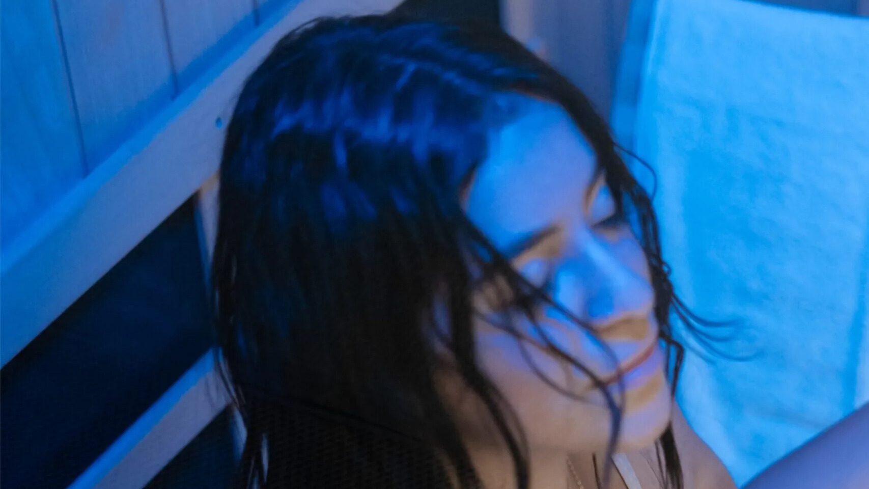 Woman meditating in blue light sauna.