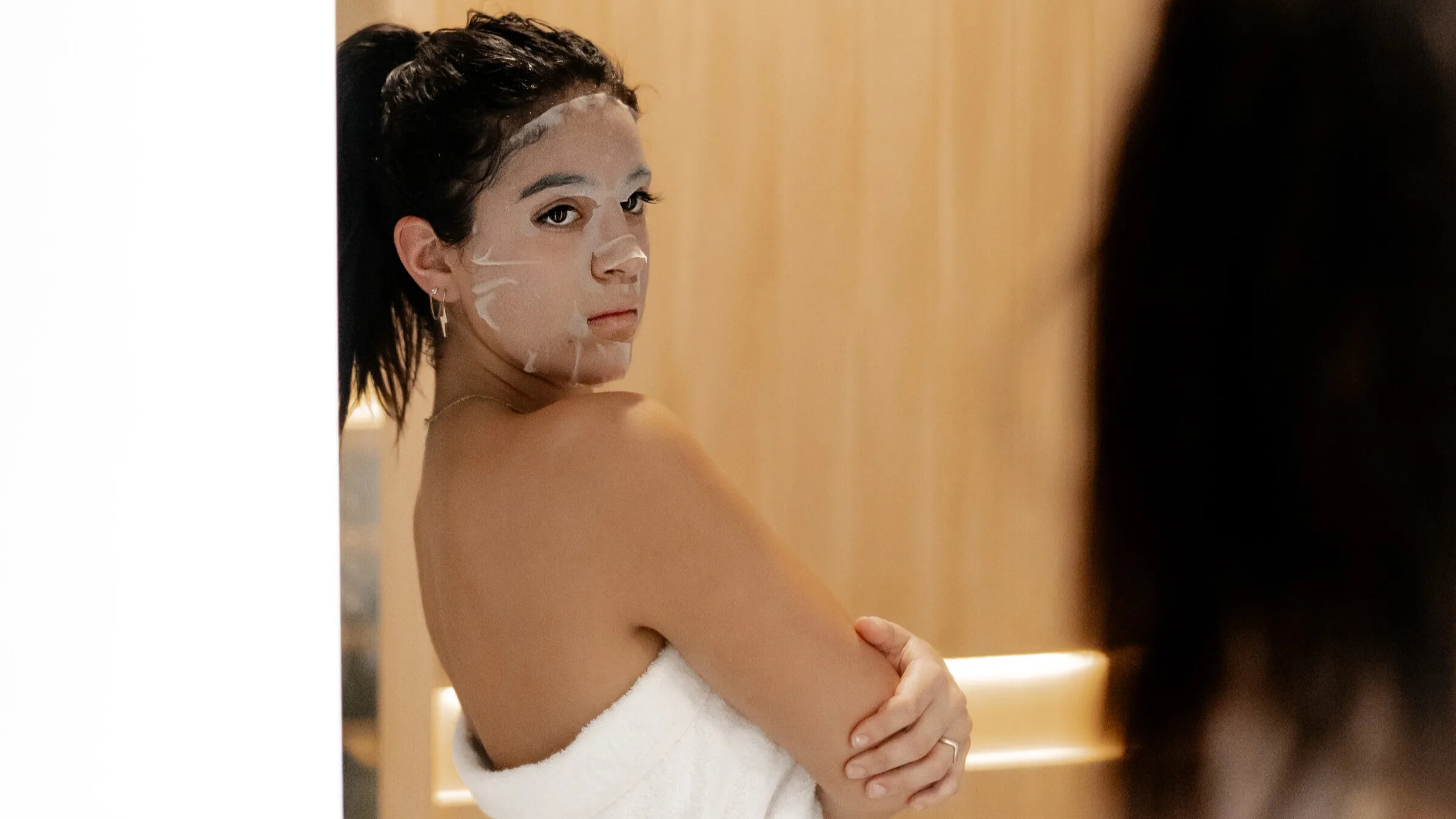 Woman using face mask skin care in sauna.